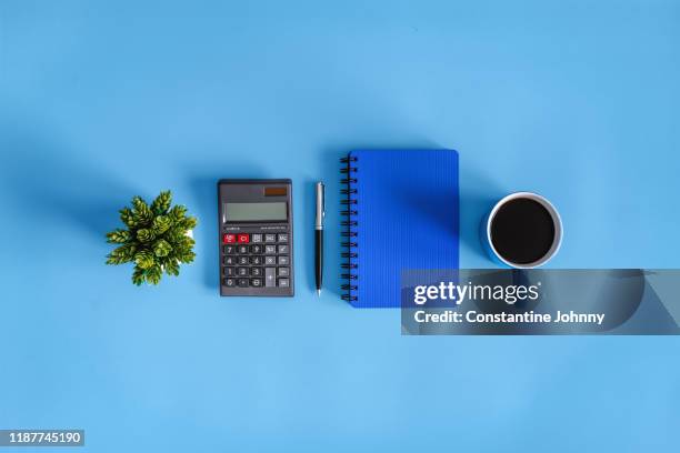 coffee break. calculator and notebook on blue desk. - neat stock-fotos und bilder