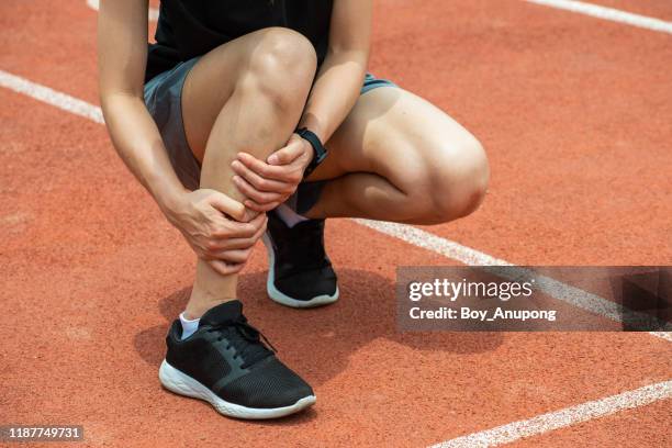 close up of runner woman holding her calf, suffering from calf pain, after running. - female muscular calves fotografías e imágenes de stock