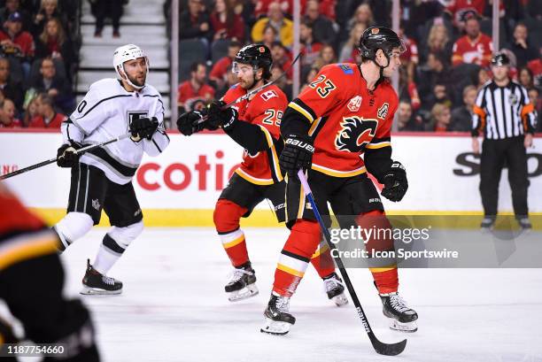 Calgary Flames Center Sean Monahan watches the play as Calgary Flames Winger Dillon Dube and Los Angeles Kings Center Michael Amadio jostle for...