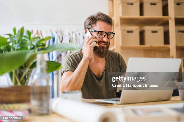 a portrait of creative man with laptop and smartphone indoors starting new small business. - zoom in stockfoto's en -beelden