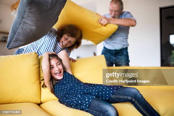 senior grandfather and granddaughter indoors on sofa, having fun. - bataille coussins photos et images de collection