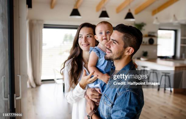 portrait of young couple with toddler girl standing indoors at home. - family apartment stock pictures, royalty-free photos & images