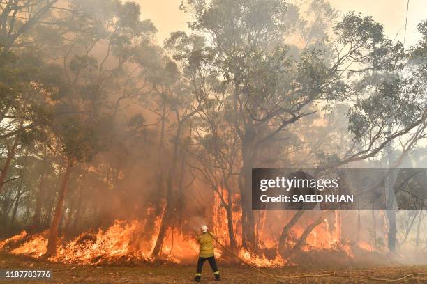 This photo taken on December 10, 2019 shows a firefighter conducting back-burning measures to secure residential areas from encroaching bushfires in...