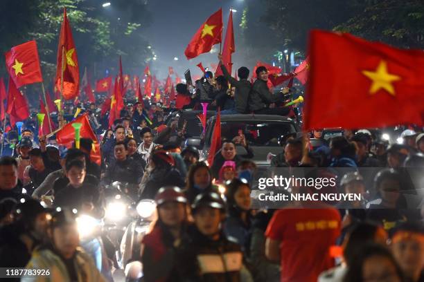 This photograph taken late December 10, 2019 shows Vietnamese fans celebrating on the streets in Hanoi following Vietnam's victory over Indonesia in...