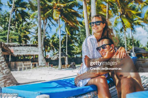 coppia rilassarsi sulla spiaggia godere di un bellissimo mare sull'isola tropicale - zanzibar foto e immagini stock
