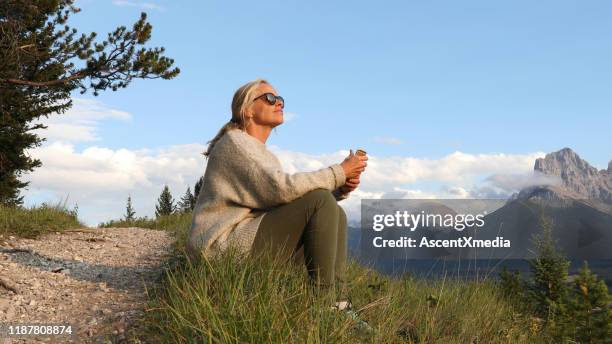 volwassen vrouw met mobiele telefoon zit bij het parcours bij zonsopgang - vervroegd pensioen stockfoto's en -beelden