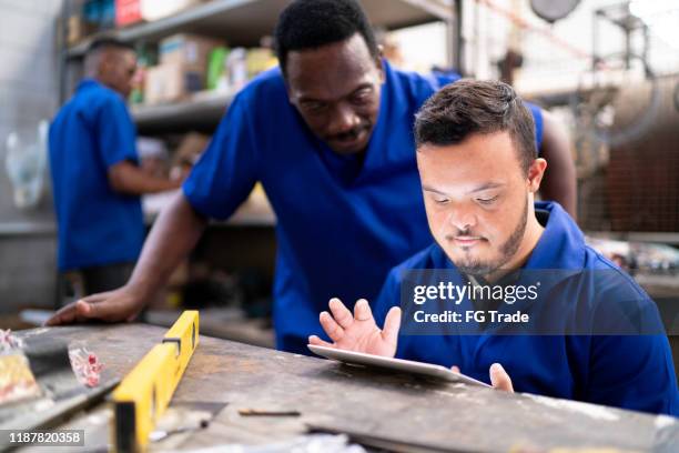 collega's die digitale tablets gebruiken en in de industrie werken - syndroom van down stockfoto's en -beelden