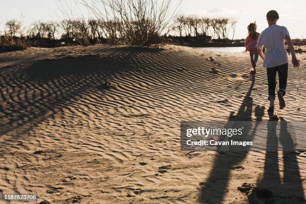 kids run across rippled sand dunes at river - bismarck north dakota stock-fotos und bilder