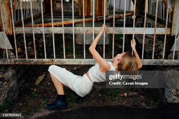 woman climbs under the fence - ontsnapping uit de gevangenis stockfoto's en -beelden
