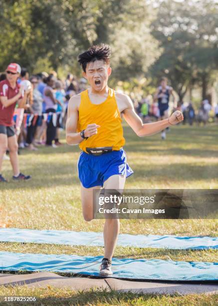 asian high school cross country runner crosses finish line emotional - exhausted at finish line stock pictures, royalty-free photos & images