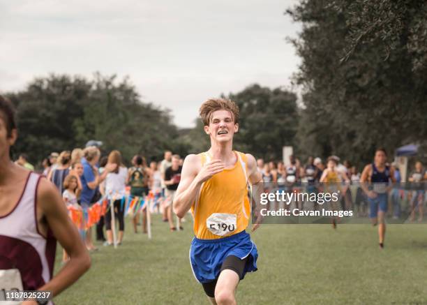 teen male cross country runner with braces crosses finish line in race - effort imagens e fotografias de stock