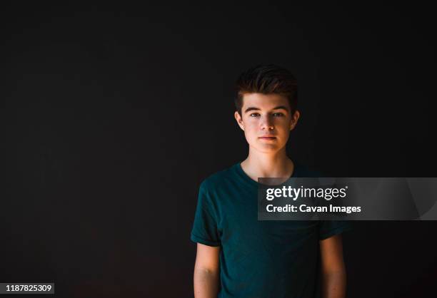 portrait of a caucasian teenage boy against a dark background. - studio portrait dark background stock-fotos und bilder