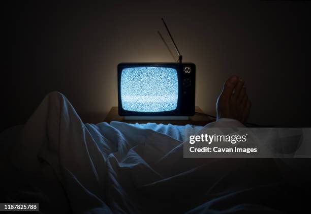 one person watches noise in tv in his bed with one foot sticking of the sheets - late night television bildbanksfoton och bilder