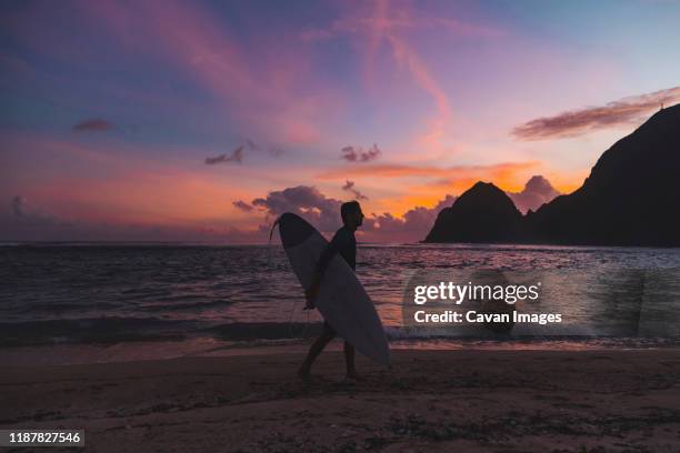 surfer at the beach at sunset time - beach night stockfoto's en -beelden