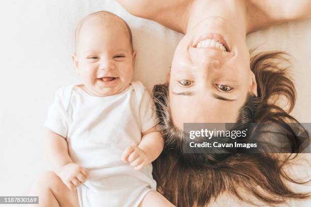 mother and newborn son stretched out in bed laughing - son massage mom imagens e fotografias de stock