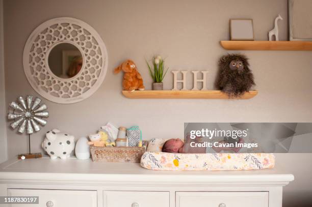 newborn baby girl laying on changing table in diaper at home - chest of drawers - fotografias e filmes do acervo