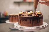 Confectioner decorating chocolate cake, close-up.