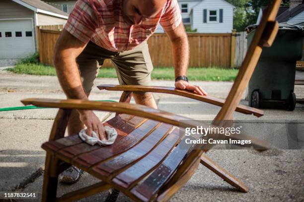 a craftsman polishes a handmade wooden chair outside - furniture wood fotografías e imágenes de stock