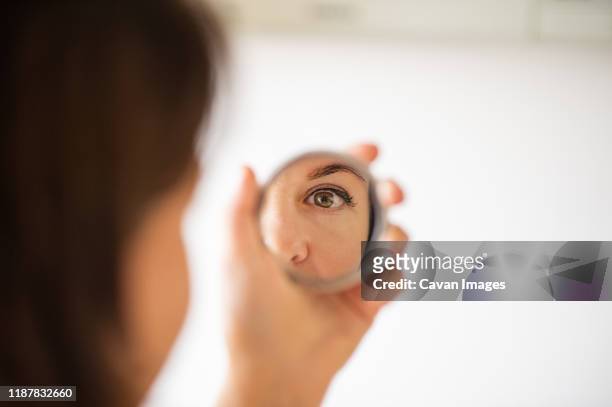 woman looking at herself in the mirror. close up shot - espejo fotografías e imágenes de stock