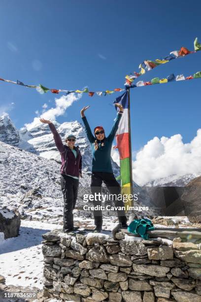 mother and daughter strike a victory pose in front of prayer flags - nepal children stock pictures, royalty-free photos & images