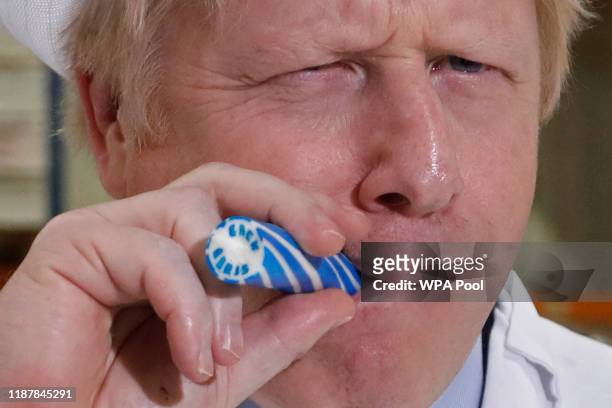 Britain's Prime Minister Boris Johnson eats a candy stick which reads "Back Boris" during a General Election campaign trail stop at Coronation Candy...