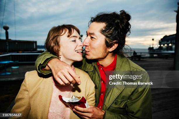 smiling couple sharing piece of chocolate while on date - happy couple flirt photos et images de collection