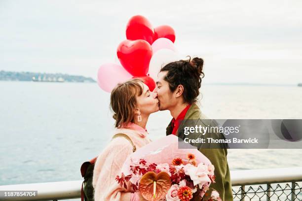 couple holding heart shaped balloons kissing while exploring city - romance flowers stock pictures, royalty-free photos & images