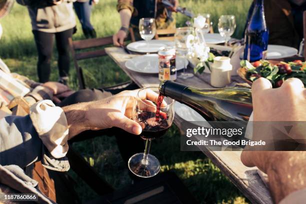 man pouring red wine into glass - red wine stockfoto's en -beelden