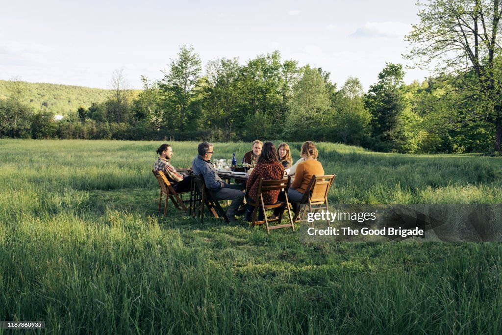 Group of friends enjoying dinner in rustic field