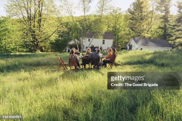 group of friends enjoying dinner in rustic field - usa diner stock pictures, royalty-free photos & images