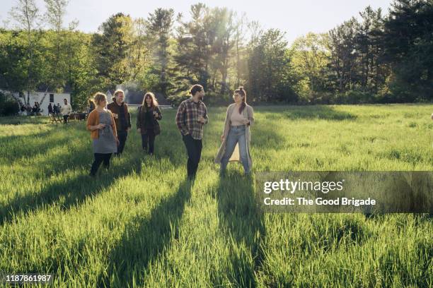 friends walking through grassy field on sunny day - wide shot of people stock pictures, royalty-free photos & images