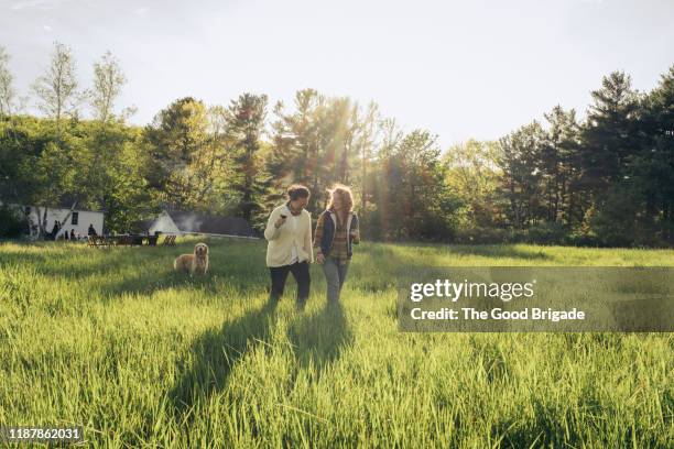 cheerful friends walking on grassy field - woman on walking in countryside stock pictures, royalty-free photos & images