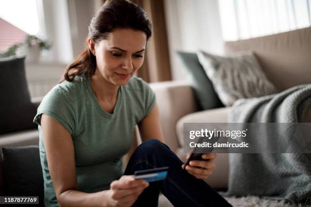 femme faisant des emplettes en ligne avec sa carte de crédit - phone credit card photos et images de collection