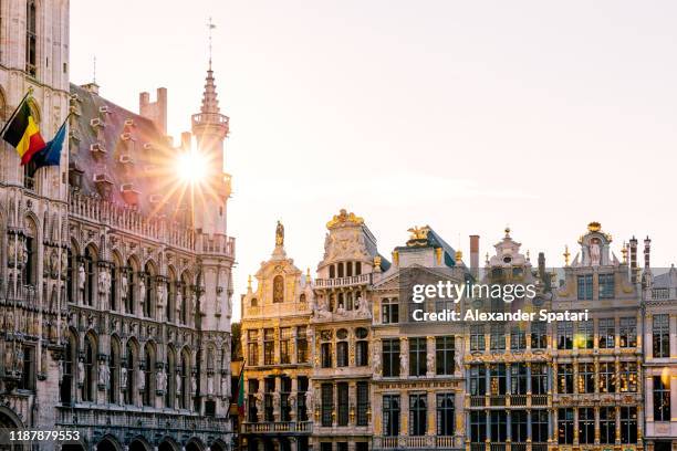 sun shining through historic buildings at grand place in brussels, belgium - mercado medieval fotografías e imágenes de stock