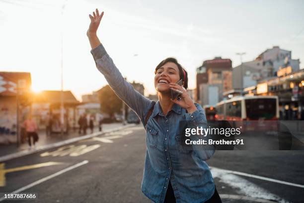 getting around the city fast - female waving on street stock pictures, royalty-free photos & images