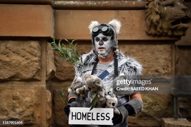 Demonstrator dressed as a "homeless koala" attends a climate protest rally in Sydney on December 11, 2019. - Up to 20,000 protesters rallied in...