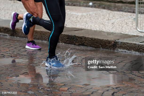 Man in black leggings runs through a puddle during the Verona Marathon on the 17th November 2019 in Verona in Italy.