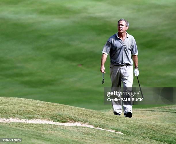 President George W. Bush, with putter and sand wedge in hand, approaches the bunker where his ball lies on the eighteenth hole at Ridgewood Country...