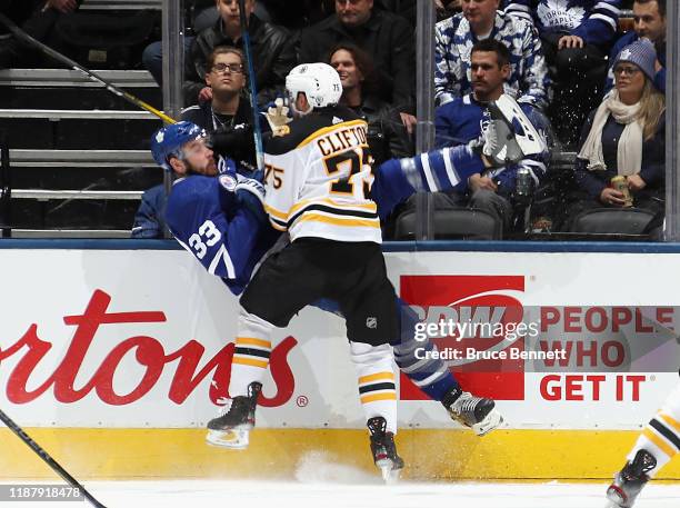 Connor Clifton of the Boston Bruins checks Frederik Gauthier of the Toronto Maple Leafs into the boards during the first period at the Scotiabank...