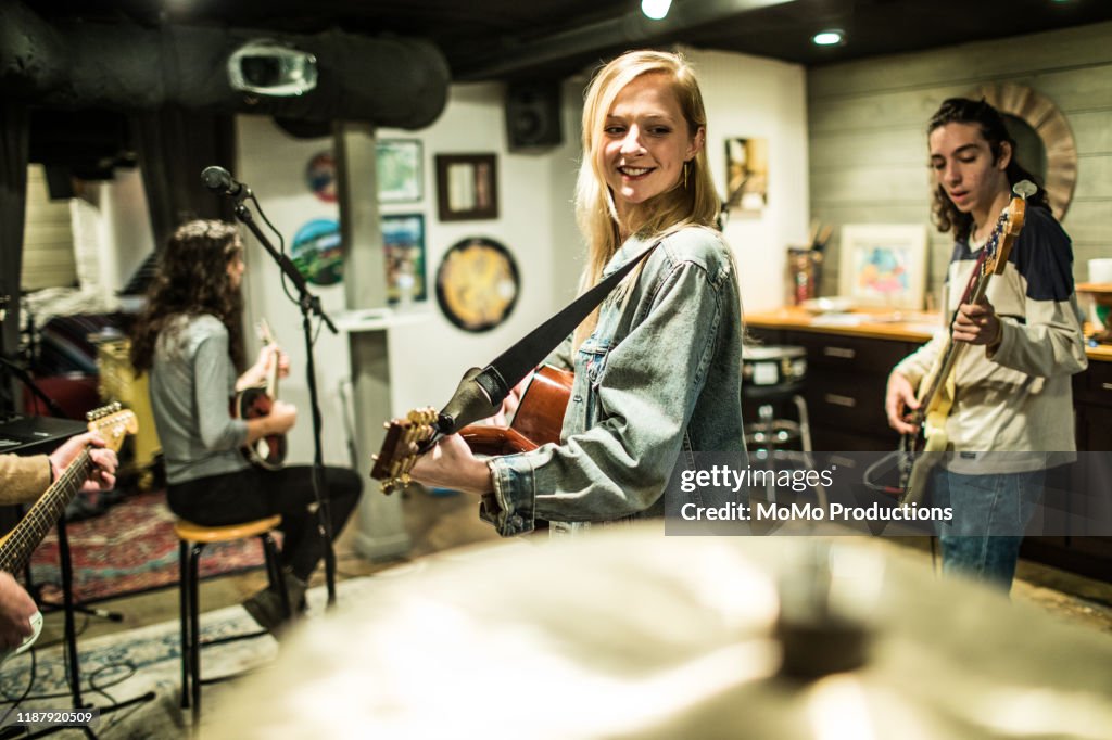 Young woman playing acoustic guitar at band rehearsal