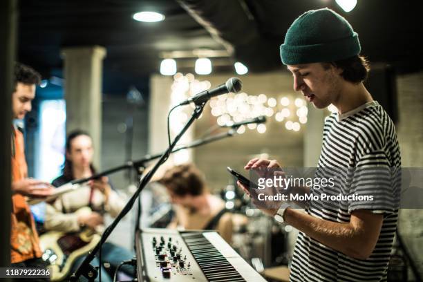 young man using mobile device at band rehearsal - musician stock pictures, royalty-free photos & images