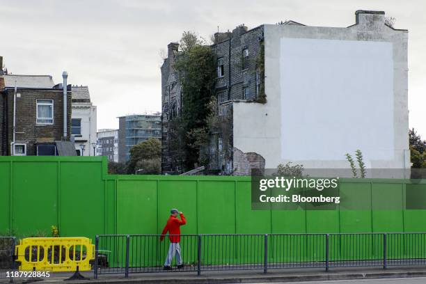 Pedestrian passes a building that until recently featured a mural by street artist Banksy depicting a European Union flag being chiseled by a workman...