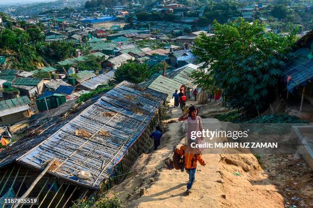 Rohingya refugee boy carries a chicken as he walks back to his makeshift house in Jamtoli refugee camp in Ukhia on December 11, 2019.