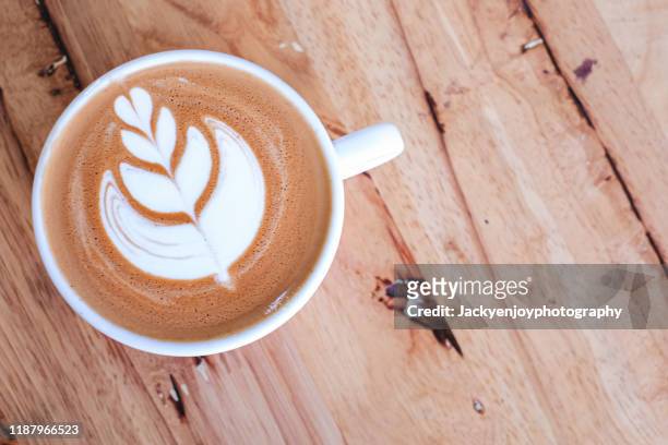 top view of a cup of coffee latte with beautiful latte art on wooden table. - coffee art stock pictures, royalty-free photos & images