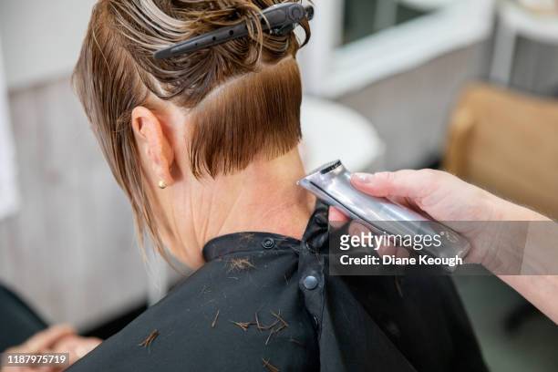 mature woman having her short hair trimmed with the clippers by the hairdresser - older woman wet hair stock pictures, royalty-free photos & images