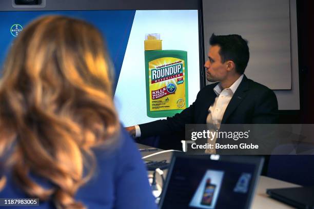 Dan Childs, Director of US External Communications for Bayer, sits in front of a screen as Bayer's Dr. S. Eliza Dunn, left, shows a bottle of Roundup...