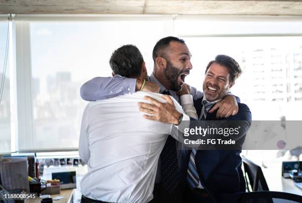 opgewonden groep van coworkes omarmen en springen tijdens een viering - argentina friendly stockfoto's en -beelden