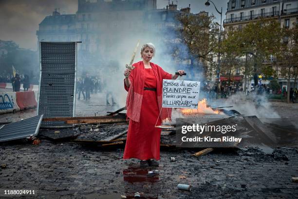 Gilet Jaune, or Yellow Vest, protestor stands next to a burning barricade at Place d'Italie as protests to mark the Anniversary of the Gilets Jaune...