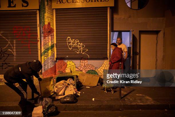Protestor pulls rubbish to block the road as local residents look on, as protests to mark the Anniversary of the Gilets Jaune movement turn violent...