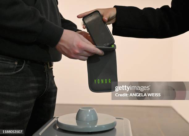 Mobile phones are locked into 'Yondr' pouches before people enter an exhibition at the Brooklyn Museum on November 22, 2019 in New York City. Yondr...